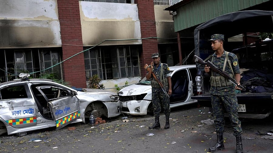 <div class="paragraphs"><p>Security force personnel stand guard next to damaged vehicles outside a police station, days after the resignation of former Bangladeshi Prime Minister Sheikh Hasina, in Dhaka, Bangladesh, August 8, 2024. </p></div>