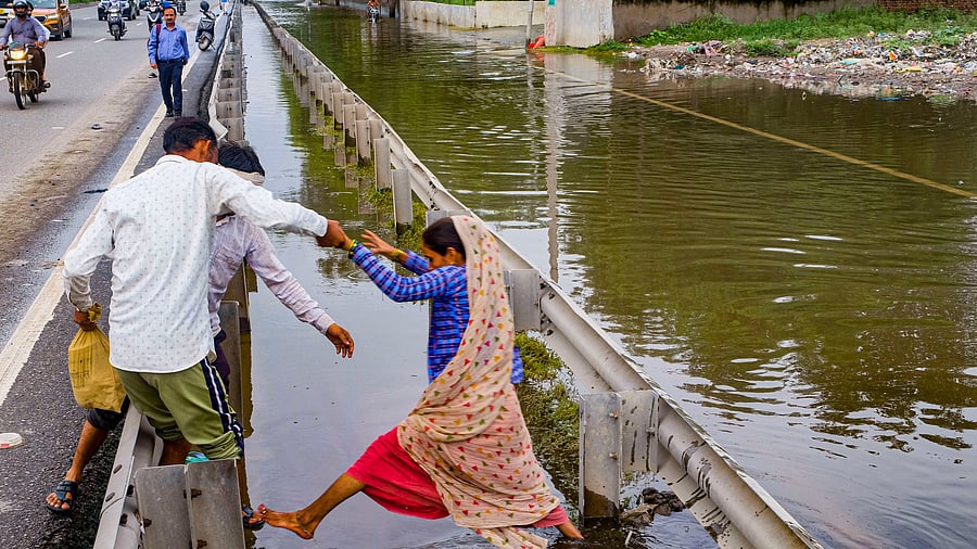 <div class="paragraphs"><p><ins>A</ins> woman tries to cross a deep drain next to the waterlogged road. </p></div>
