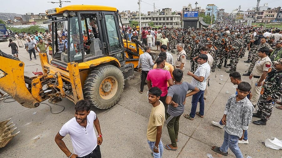 <div class="paragraphs"><p>Residents gather near a bulldozer as they try to stop a demolition drive by the MCD in Bhalswa area of New Delhi on August 13. </p></div>