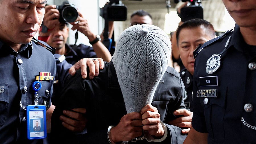 <div class="paragraphs"><p>A man linked to Global Ikhwan Service and Business Holdings (GISB) covers his face as he is escorted by police officers after being charged in a court in Putrajaya, Sept 18, 2024.</p></div>