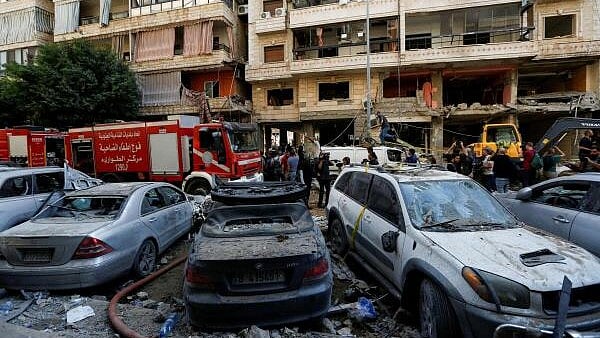 <div class="paragraphs"><p>People gather near a firetruck and damaged vehicles at the site of Friday's Israeli strike, as search and rescue operations continue, in Beirut's southern suburbs, Lebanon.&nbsp;</p></div>