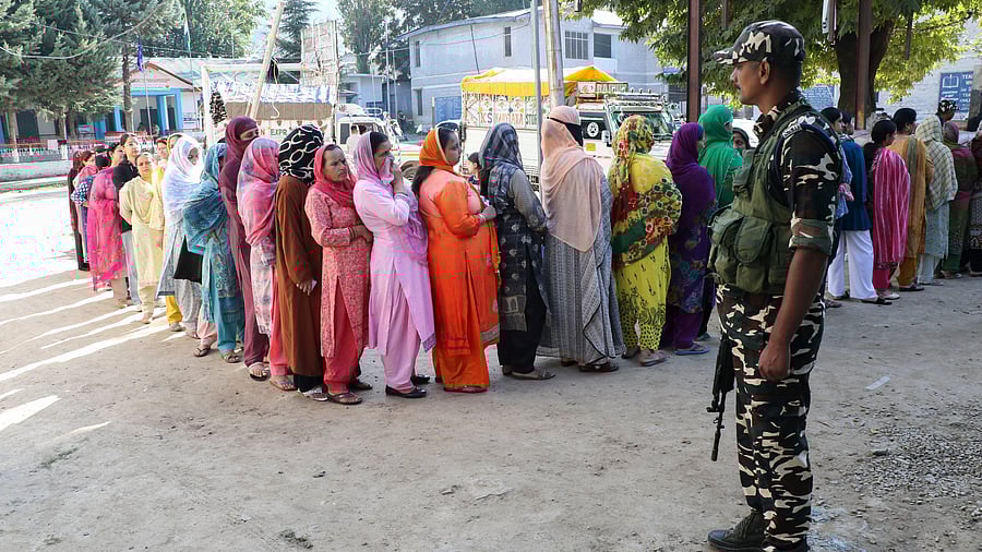 <div class="paragraphs"><p>A security official stands guard as voters stand in a queue to cast votes during the first phase of Jammu and Kashmir Assembly elections.</p></div>