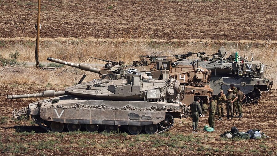 <div class="paragraphs"><p>People stand next to Israeli Army tanks, amid cross-border hostilities between Hezbollah and Israel, in northern Israel.</p></div>