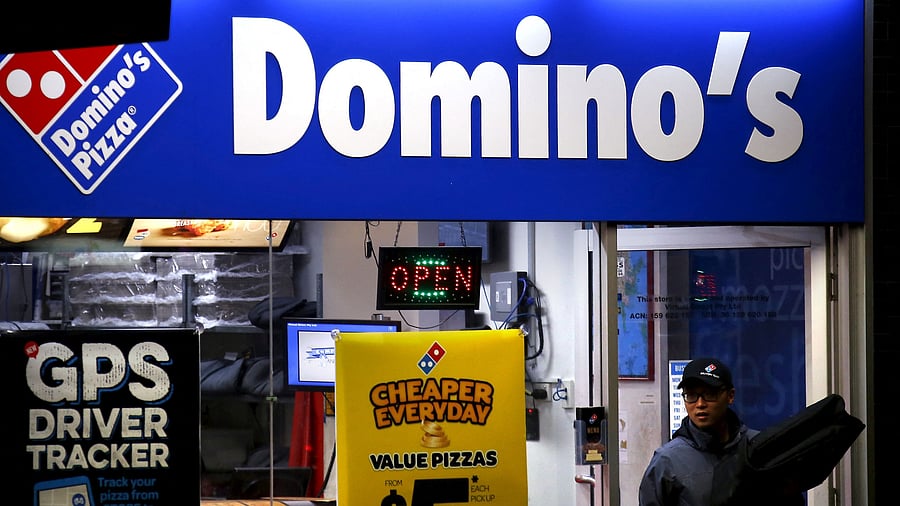 <div class="paragraphs"><p>A worker carries a pizza for delivery as he exits a Domino's pizza store.</p></div>