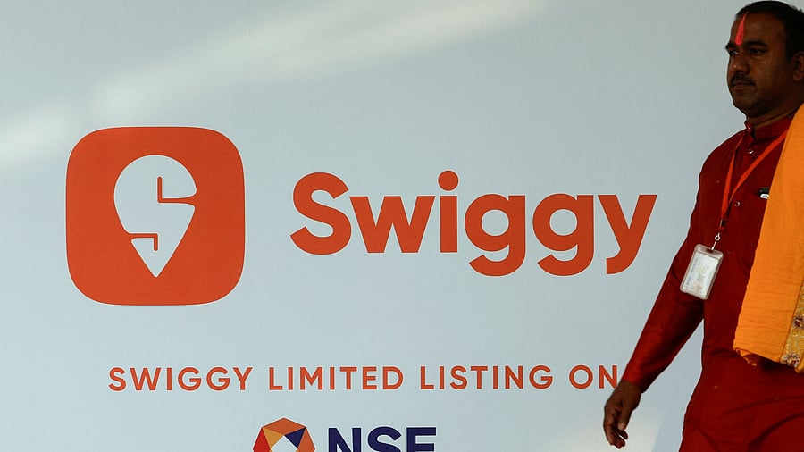 <div class="paragraphs"><p>A priest walks past a logo of Swiggy ahead of its Initial Public Offering in Mumbai.</p></div>
