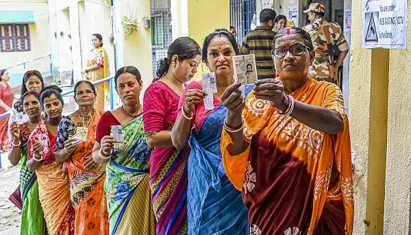 <div class="paragraphs"><p>Voters show their ID cards as they wait to cast their votes.</p></div>