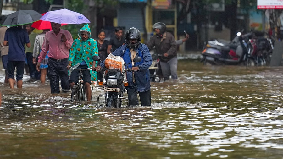 <div class="paragraphs"><p>Commuters wade through a waterlogged road amid showers, in Chennai, on Saturday.</p></div>