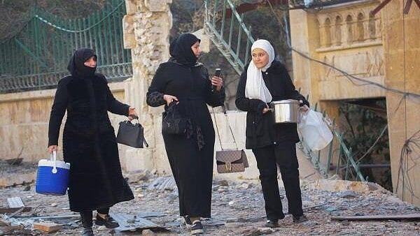 <div class="paragraphs"><p>Women walk along a damaged site in Aleppo, after the Syrian army said that dozens of its soldiers had been killed in a major attack by rebels who swept into the city, in Syria.</p></div>