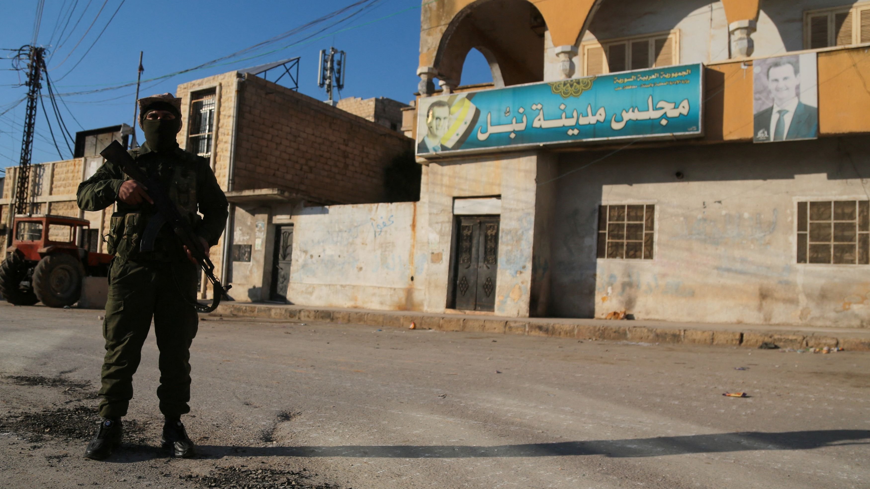 <div class="paragraphs"><p>A rebel fighter holds his weapon as he stands near Nubl's city council, as a picture of Syria's President Bashar al-Assad hangs on the building in Nubl, north of Aleppo, Syria December 2.</p></div>