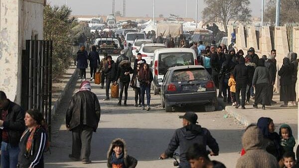 <div class="paragraphs"><p>Displaced people who fled the Aleppo countryside walk past cars in Tabqa, Syria December 4, 2024. </p></div>