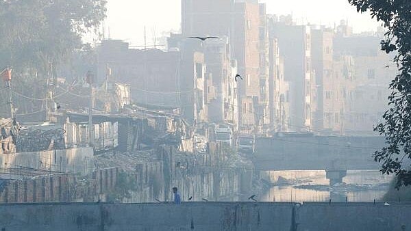 <div class="paragraphs"><p>A man walks on a footbridge across an open drainage channel, as the sky is enveloped in smog caused by air pollution, in New Delhi.&nbsp;</p></div>
