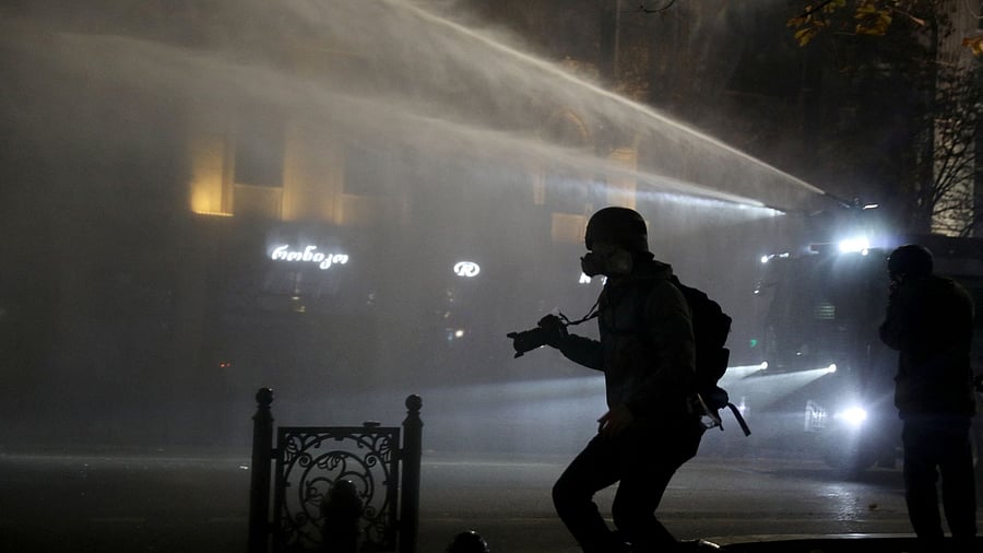<div class="paragraphs"><p>A photographer jumps off the curb as police officers use a water cannon to disperse supporters of Georgia's opposition parties during a rally to protest against the government's decision to suspend talks on joining the European Union in Tbilisi, Georgia.</p></div>