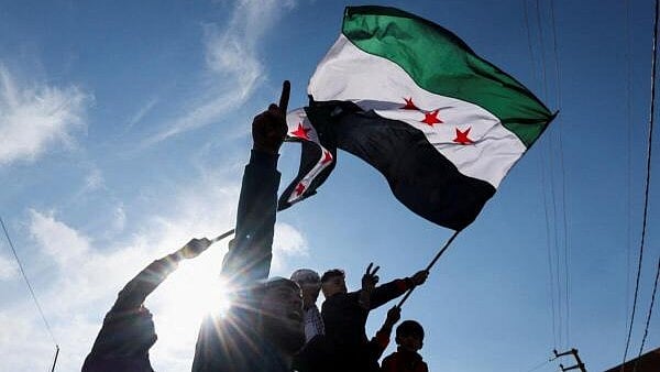<div class="paragraphs"><p>A person waves a Syrian opposition flag as people celebrate at Masnaa Border Crossing</p></div>