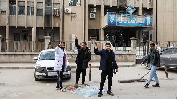 <div class="paragraphs"><p>People gesture near a picture of Syrian President Bashar al-Assad, after Syrian rebels announced that they have ousted President Bashar al-Assad, in Qamishli, Syria December 8, 2024.</p></div>