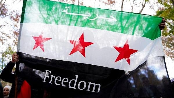 <div class="paragraphs"><p>A person holds a Syrian opposition flag with words "Freedom" on it during a demonstration celebrating the fall of Bashar Al-Assad regime</p></div>