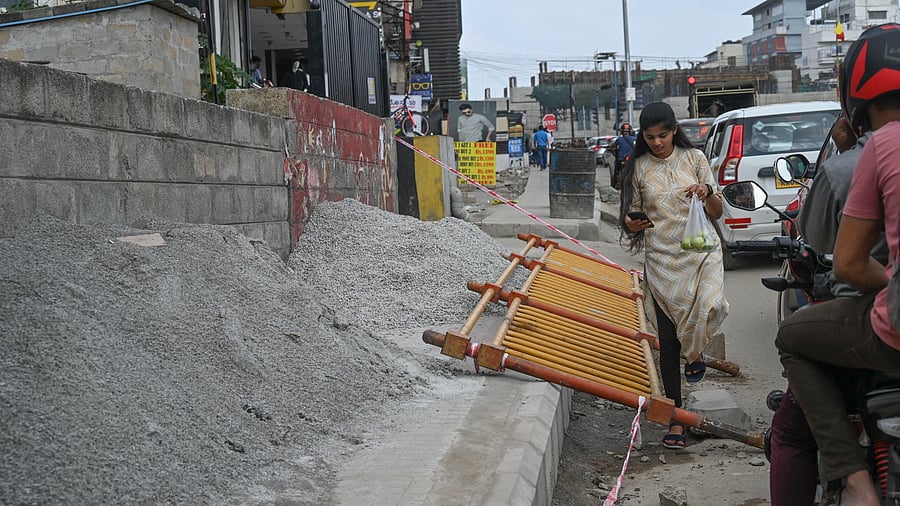 When footpaths are unusable, like this one on the Outer Ring Road in Marathahalli, people are forced to walk on the road, putting them at great risk. DH Photo/SK Dinesh