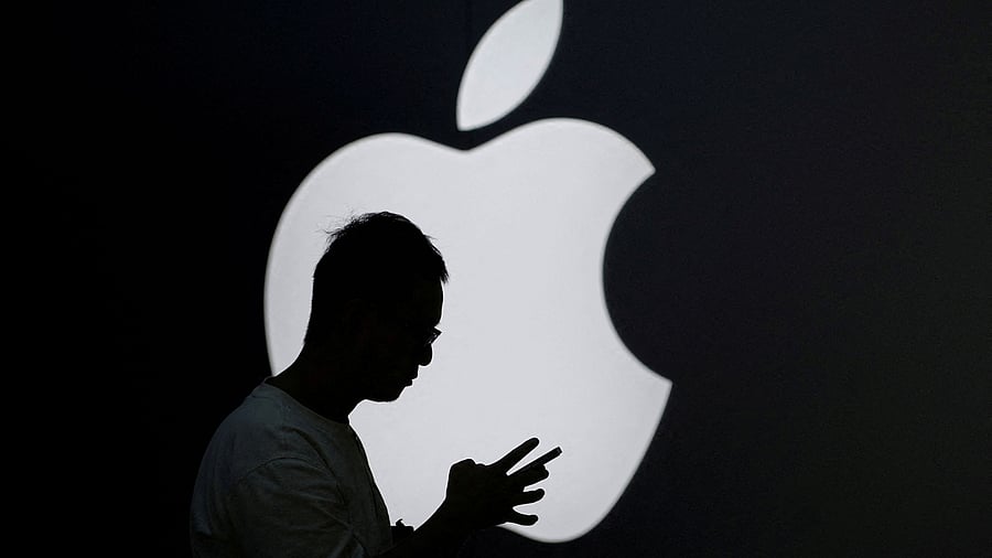 <div class="paragraphs"><p> A man check his phone near an Apple logo outside its store</p></div>