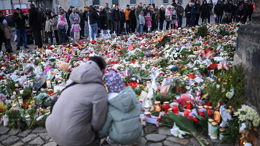 <div class="paragraphs"><p>People look at flowers and candles left as a tribute near the Christmas market, where a man drove a car into the crowd through an emergency exit route in Magdeburg. </p></div>