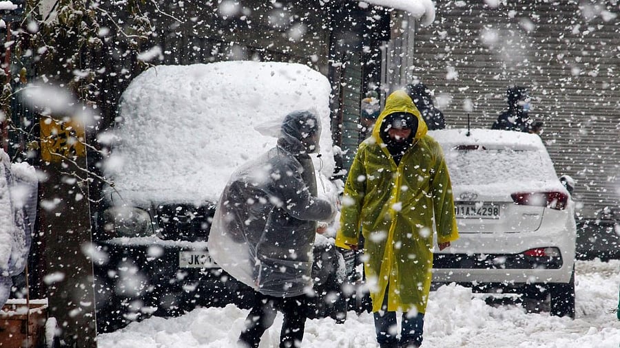 <div class="paragraphs"><p>Srinagar: Pedestrians walk on a snow-covered road during heavy snowfall.</p></div>