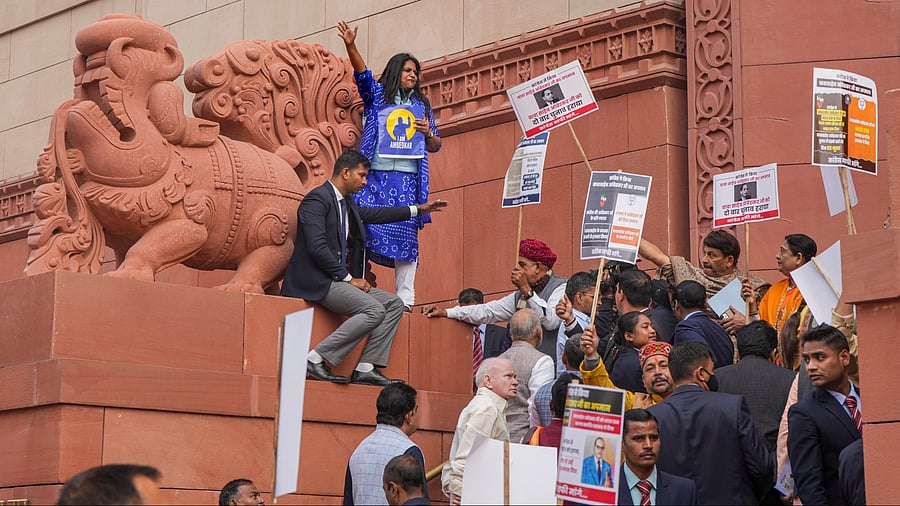 <div class="paragraphs"><p>Congress MP Jebi Mather climbs atop the 'Makar Dwar' as NDA members hold placards during a protest by I.N.D.I.A. Bloc as well as NDA members, at Parliament complex, in New Delhi over Amit Shah's Ambedkar remarks</p></div>