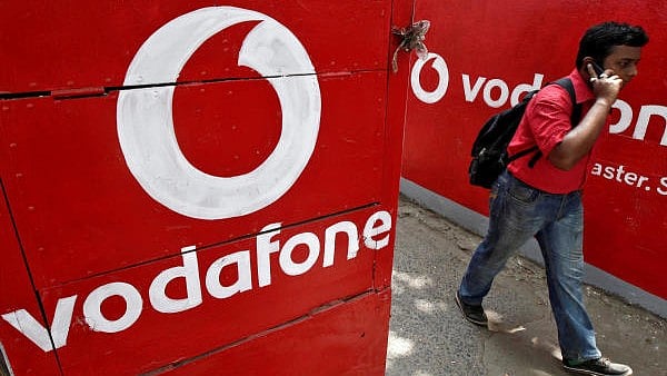 <div class="paragraphs"><p>A man speaks on his mobile phone as he walks past logos of Vodafone painted on a roadside wall.</p></div>