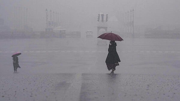 <div class="paragraphs"><p>People move amid rain at Vijay Chowk, in New Delhi. </p></div>