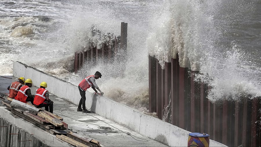 <div class="paragraphs"><p>Mumbai: Construction workers at Marine Drive as high tidal waves lash the shore ahead of the landfall of Cyclone Biparjoy, in Mumbai, Thursday, June 15, 2023. </p></div>