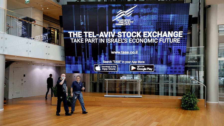 <div class="paragraphs"><p>Men walk past an electronic board at the Tel Aviv Stock Exchange</p></div>