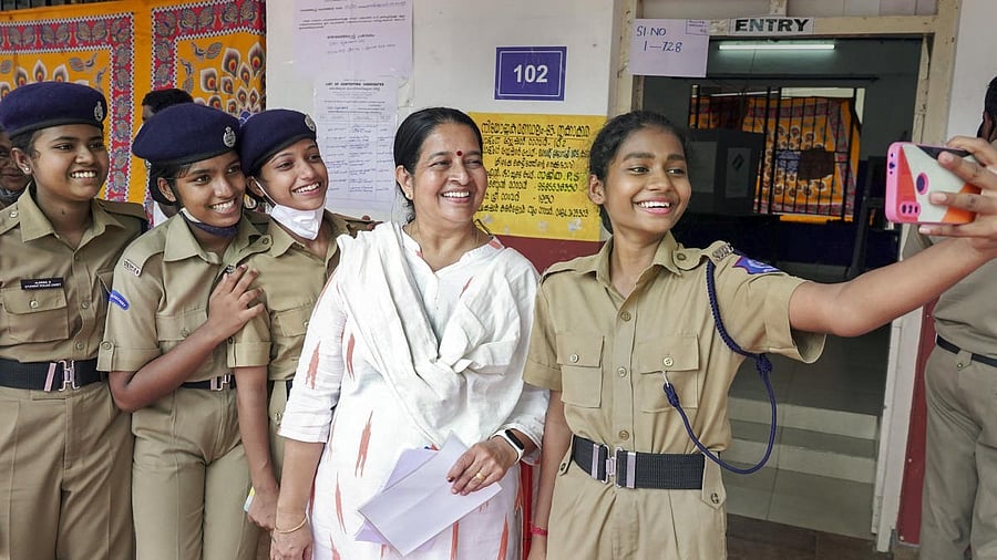 <div class="paragraphs"><p>Uma Thomas, in white, clicks photos with student police cadets during 2022 bypolls </p></div>