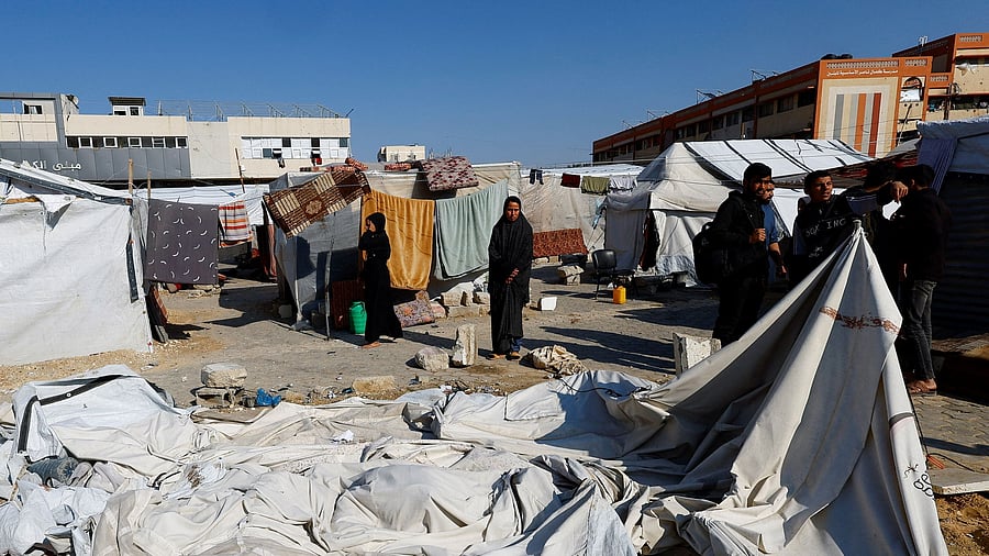 <div class="paragraphs"><p>Palestinians stand near damaged tents for displaced people following an Israeli strike on Hamas-run Interior Ministry headquarters in Khan Younis.</p></div>