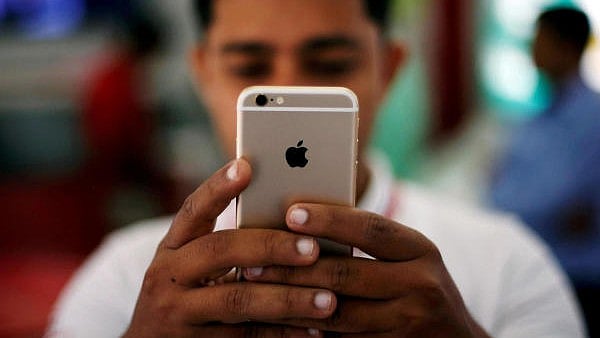 <div class="paragraphs"><p>A salesman checks a customer's iPhone at a mobile phone store in New Delhi</p></div>