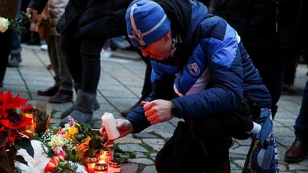<div class="paragraphs"><p>A man lights a candles as people leave floral tributes to the victims near the site where a car rammed into a crowd at a Magdeburg Christmas market in Magdeburg, Germany December 21, 2024.</p></div>