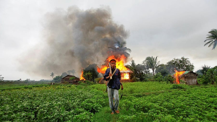 <div class="paragraphs"><p> An ethnic Rakhine man holds homemade weapons as he walks in front of burning houses in&nbsp;Sittwe.</p></div>