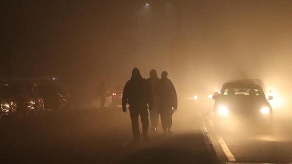 <div class="paragraphs"><p>Commuters amid low visibility due to fog on a cold winter morning.</p></div>