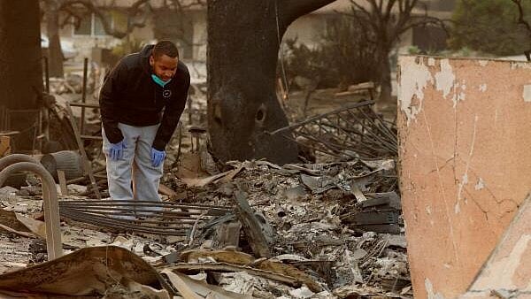 <div class="paragraphs"><p>Jestin Willard inspects the debris of his home burnt down by the Eaton Fire in Altadena, California, US </p></div>