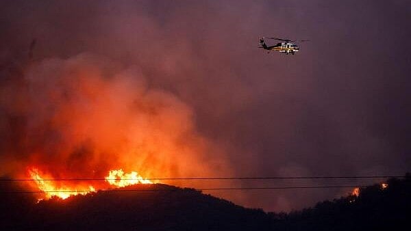 <div class="paragraphs"><p>An helicopter flies as smoke and fire billow from the Palisades Fire threatening homes in the Brentwood area of Los Angeles, California, U.S., January 11, 2025. </p></div>