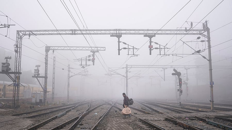 <div class="paragraphs"><p>A commuter crosses tracks at a railway station amid dense fog during a cold winter morning.</p></div>