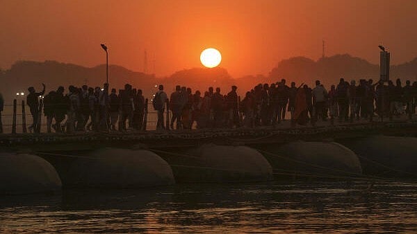 <div class="paragraphs"><p>Devotees crossing a pontoon bridge over the Ganga river are silhouetted against the setting sun during the ongoing ‘Maha Kumbh Mela’ festival in Prayagraj, Uttar Pradesh.</p></div>