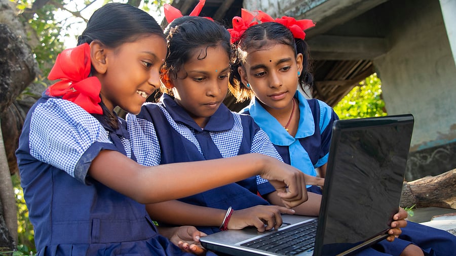 Indian village government school girls operating laptop computer systems in rural area in India