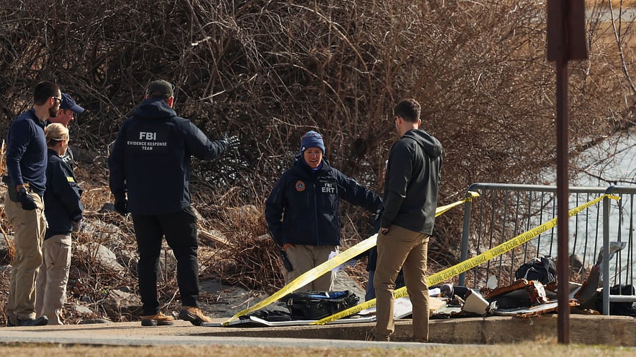 <div class="paragraphs"><p>FBI agents stand near debris, after American Eagle flight 5342 collided with a Black Hawk helicopter while approaching Ronald Reagan Washington National Airport and crashed into Potomac River, in Arlington, Virginia.</p></div>