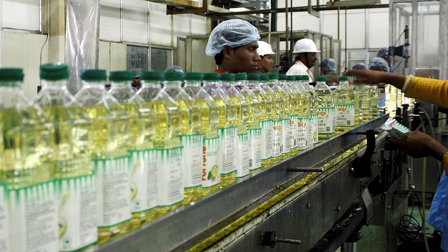 <div class="paragraphs"><p> Employees fill plastic bottles with edible oil at an oil refinery plant of Adani Wilmar Ltd</p></div>