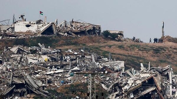 <div class="paragraphs"><p>A Palestinian flag flutters as people walk near buildings in ruins in Gaza, amid a ceasefire between Israel and Hamas, as seen from Israel, February 11, 2025.</p></div>