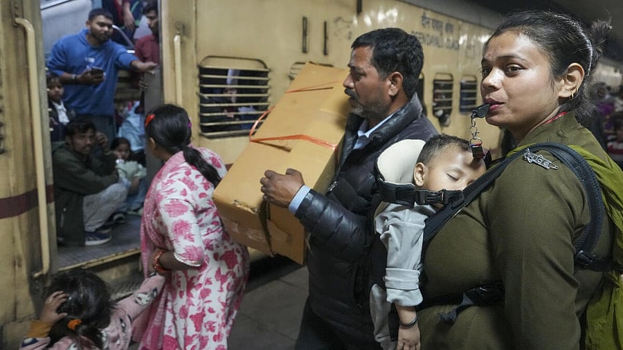<div class="paragraphs"><p>A RPF official carrying her child manages a crowd of passengers at the New Delhi Railway Station, in New Delhi, Sunday, Feb. 16, 2025. At least 18 people were killed and more than a dozen injured in a stampede that broke out late Saturday night at the crowded railway station in the national capital.</p></div>