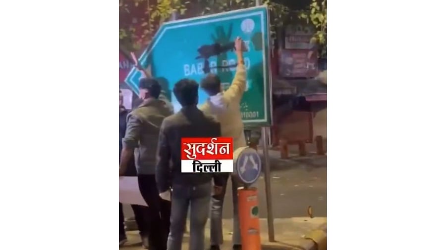 <div class="paragraphs"><p>A screengrab from the video showing people applying black spray on the signboards</p></div>