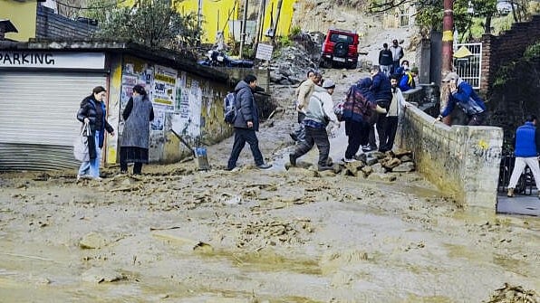 <div class="paragraphs"><p>People cross a debris-strewn road after heavy rain, in Kullu, Himachal Pradesh, Saturday, March 1, 2025.</p></div>