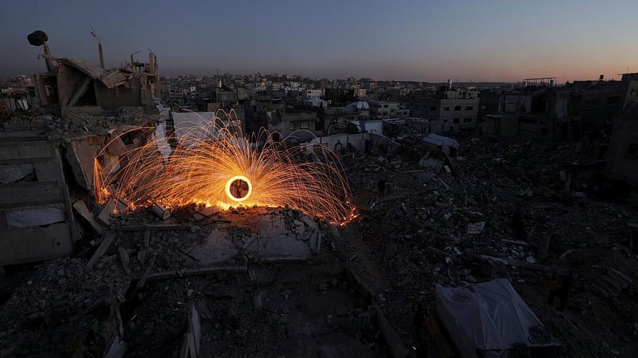 <div class="paragraphs"><p>A person spins a steel wool sparkler amid the rubble of buildings, ahead of the holy fasting month of Ramadan.</p></div>