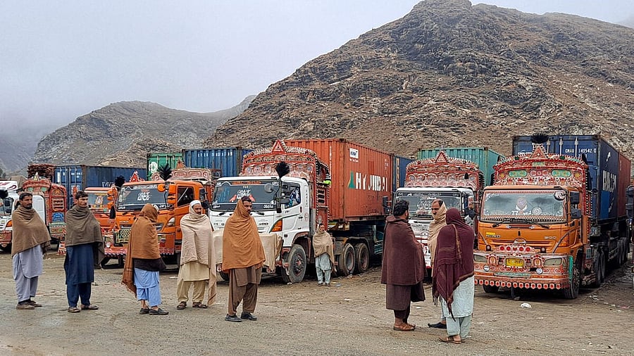 <div class="paragraphs"><p>People stand next to parked trucks loaded with supplies at the Torkham border</p></div>