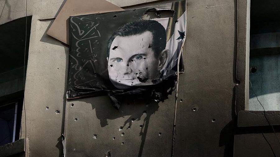 <div class="paragraphs"><p>A picture of Bashar al-Assad, damaged by bullets, hangs on the wall of a burnt building of Criminal Security department.</p></div>