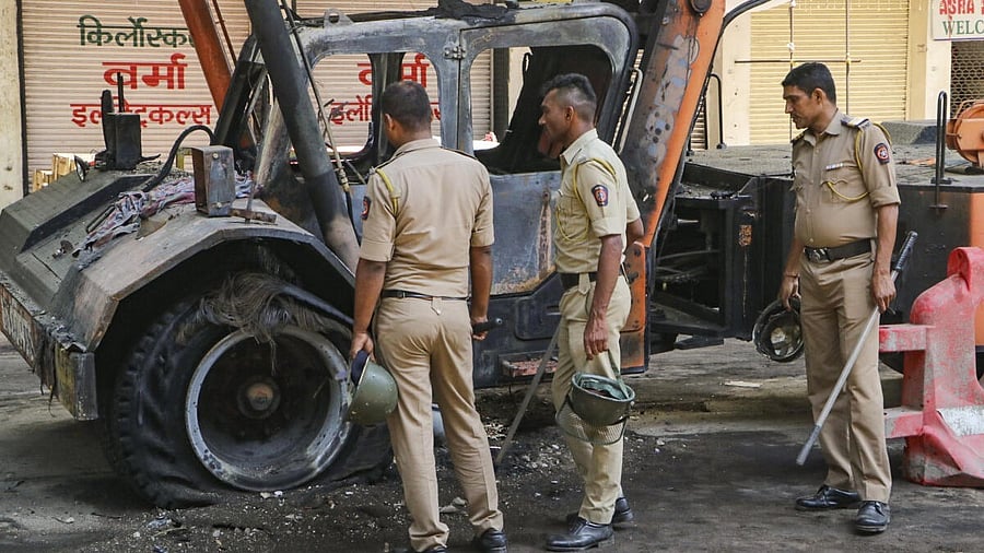 <div class="paragraphs"><p>Police personnel near charred remains of a vehicle, a day after violence broke out following an agitation by a right-wing group demanding removal of Aurangzeb's tomb, in Nagpur.</p></div>