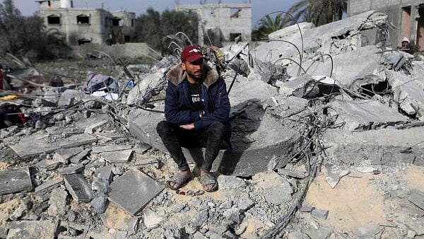 <div class="paragraphs"><p>A man sits amid rubble as Palestinians inspect the site of an Israeli strike on a house, in Khan Younis in the southern Gaza Strip March 20, 2025.</p></div>
